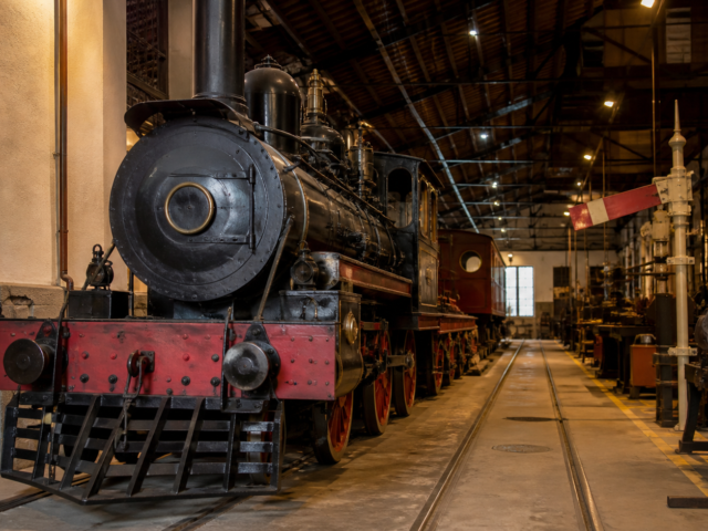 Locomotora histórica conservada en un museo ferroviario mexicano con vías y herramientas de taller